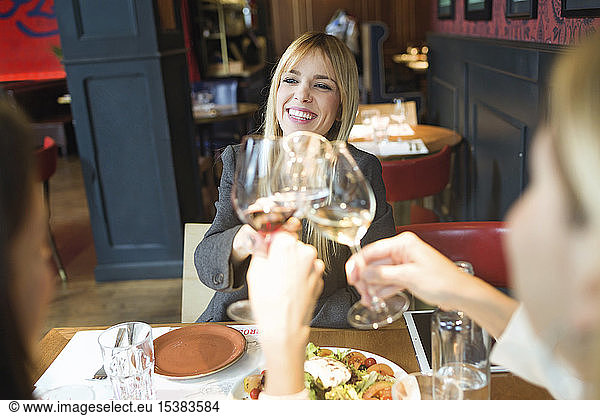 Smiling businesswomen meeting and clinking wine glasses in a restaurant