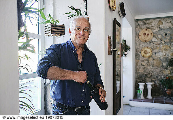 Smiling cafe owner standing with wine bottle