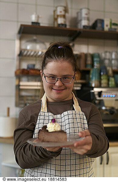 Smiling cafe owner with down syndrome giving slice of cake