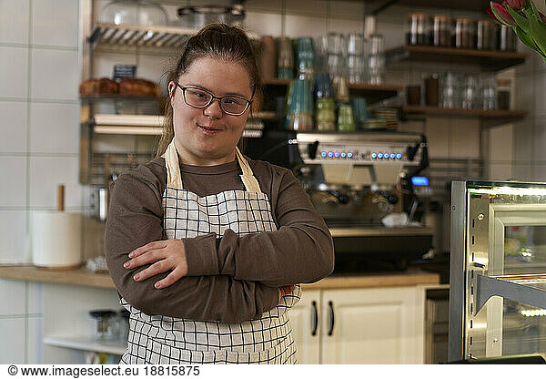 Smiling cafe owner with down syndrome standing in coffee shop