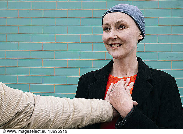 Smiling cancer patient with man's hand on chest
