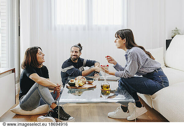 Smiling clients discussing with nutritionist sitting on sofa at home