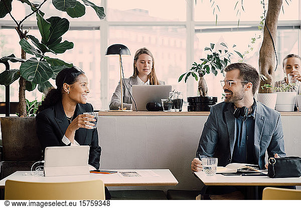 Smiling colleagues talking while sitting at coworking space