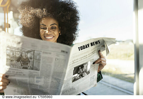 Smiling commuter reading newspaper and traveling to work
