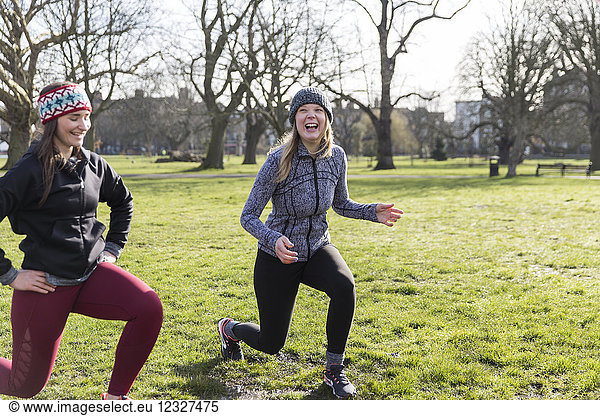 Smiling  confident women doing lunges in sunny park