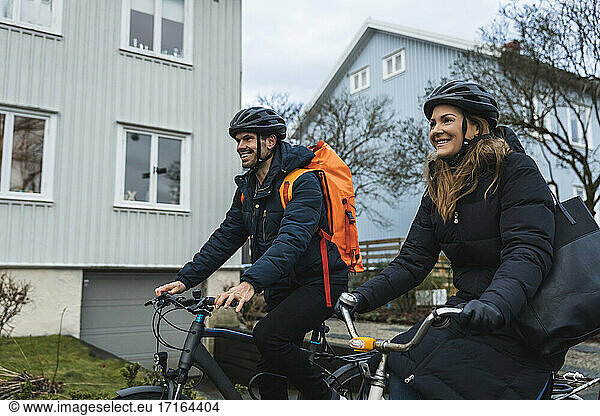 Smiling couple cycling while exploring city