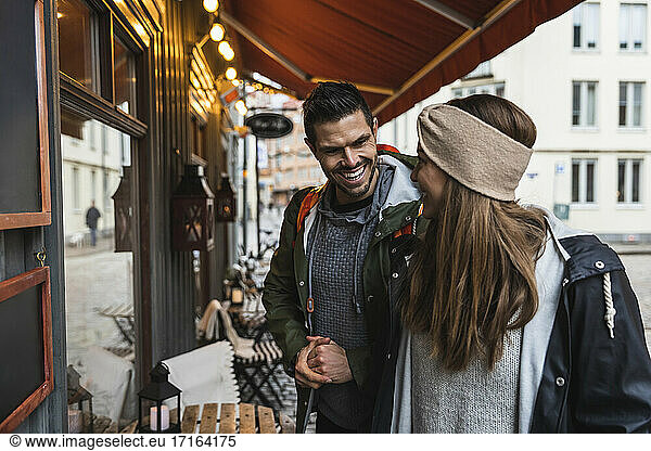 Smiling couple doing window shopping while standing outside store