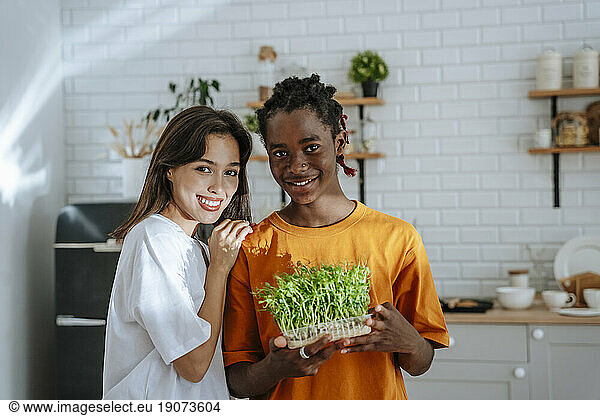 Smiling couple holding homegrown herbs in kitchen