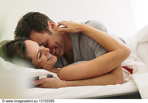Smiling couple in bed at home