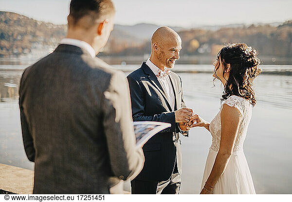 Smiling couple looking at each other while exchanging ring
