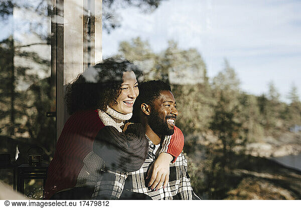Smiling couple looking away seen through window