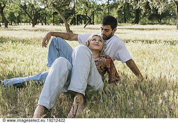 Smiling couple lying on grass on sunny day