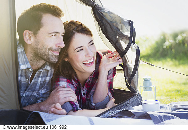 Smiling couple peering from inside tent