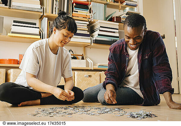 Smiling couple playing jigsaw puzzle on floor at home