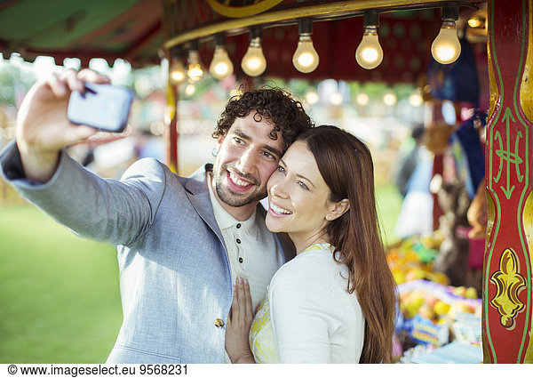 Smiling couple taking selfie in amusement park