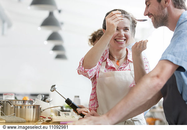 Smiling couple tasting food in cooking class kitchen