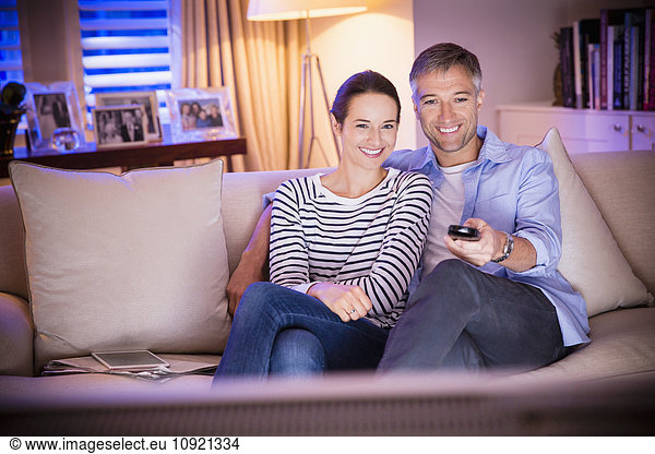 Smiling couple watching TV in living room
