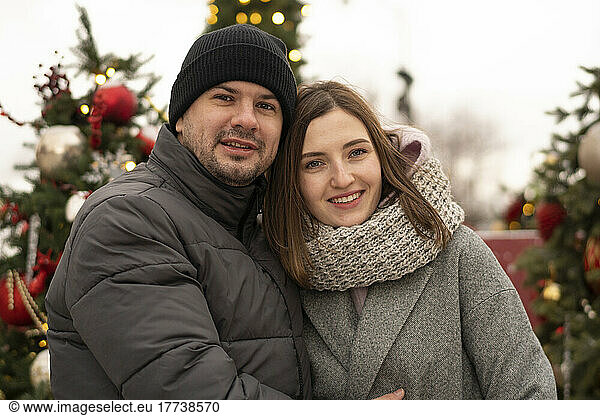 Smiling couple wearing warm clothing at Christmas market