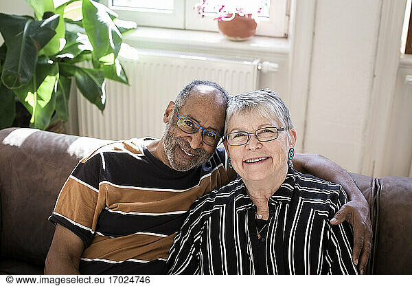 Smiling couple with arm around sitting on sofa at home