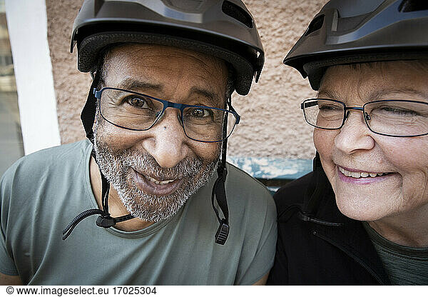 Smiling couple with cycling helmet outside house
