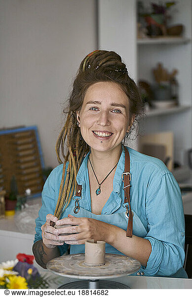 Smiling craftswoman making craft product at workshop