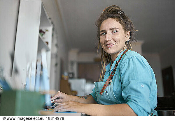 Smiling craftswoman sitting in workshop