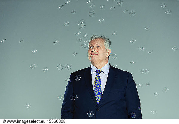 Smiling  curious businessman watching falling bubbles