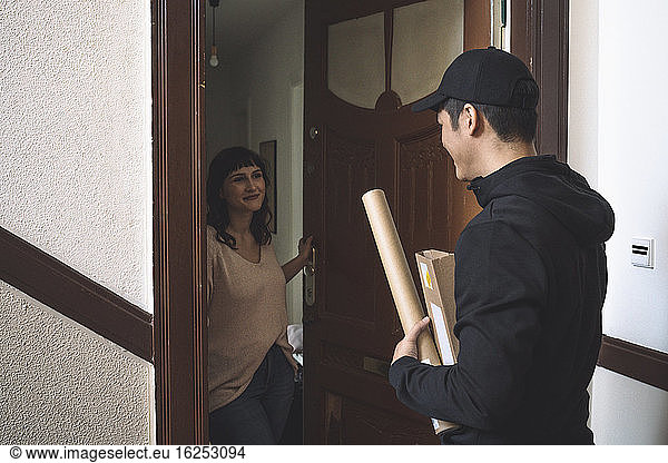 Smiling customer talking to delivery man at doorstep