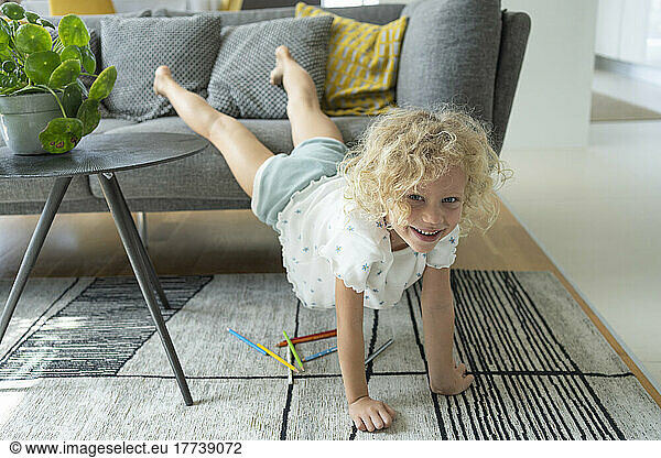 Smiling cute blond girl playing in living room at home