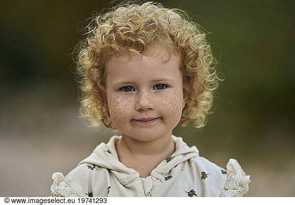 Smiling cute blond girl with freckles on face