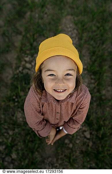 Smiling cute girl wearing knit hat standing on agricultural field