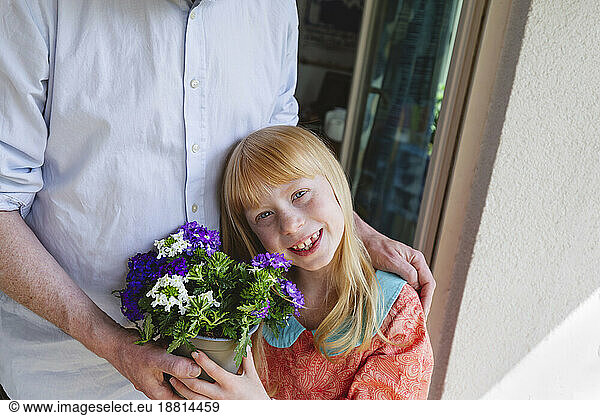 Smiling daughter holding potted plant by father