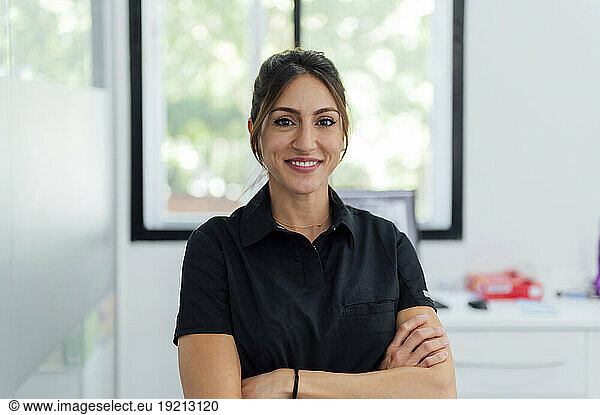 Smiling dentist with arms crossed in clinic