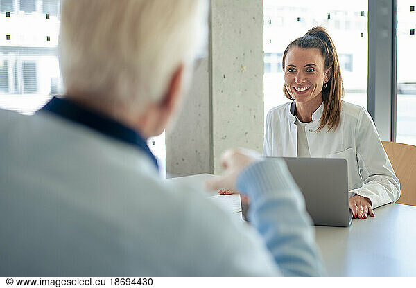 Smiling doctor discussing with patient at clinic