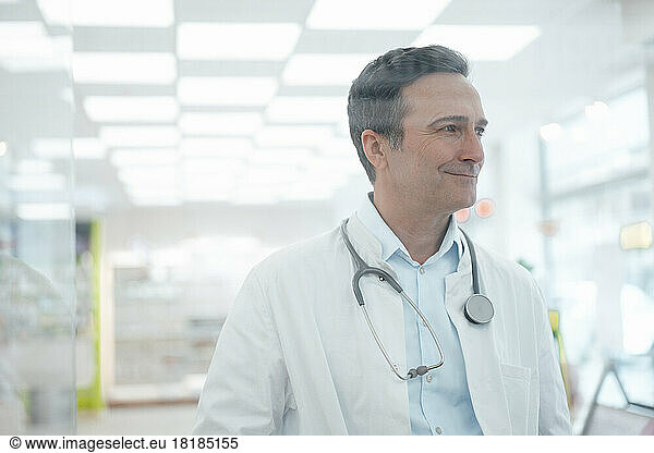 Smiling doctor with stethoscope seen through glass
