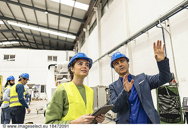 Smiling engineer explaining colleague in factory