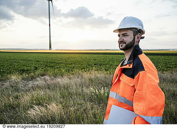 Smiling engineer wearing reflective clothing at wind farm