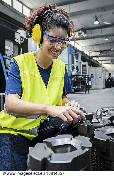Smiling engineer wearing reflective clothing working in modern factory