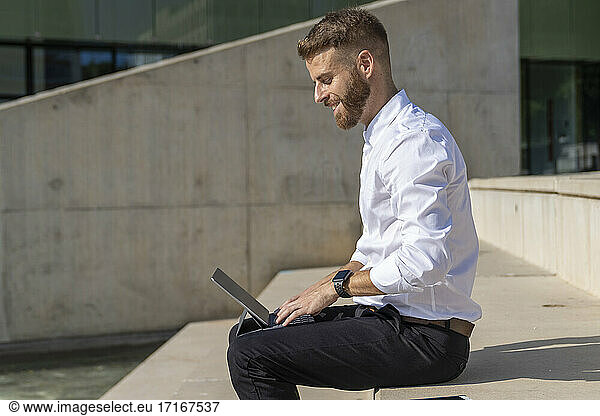 Smiling entrepreneur using digital tablet while sitting on steps