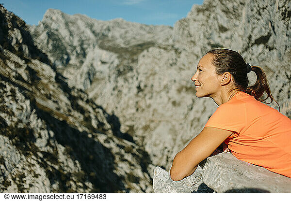 Smiling explorer looking away while lying on rock at Cares Trail in Picos De Europe National Park  Asturias  Spain