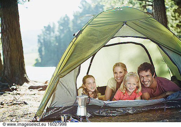 Smiling family inside of tent in woods