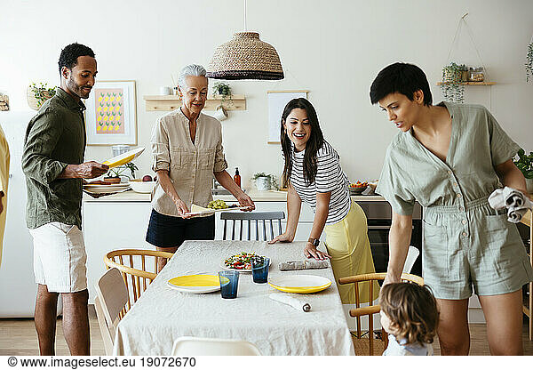 Smiling family setting table in kitchen