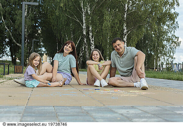 Smiling family sitting and enjoying on footpath at park