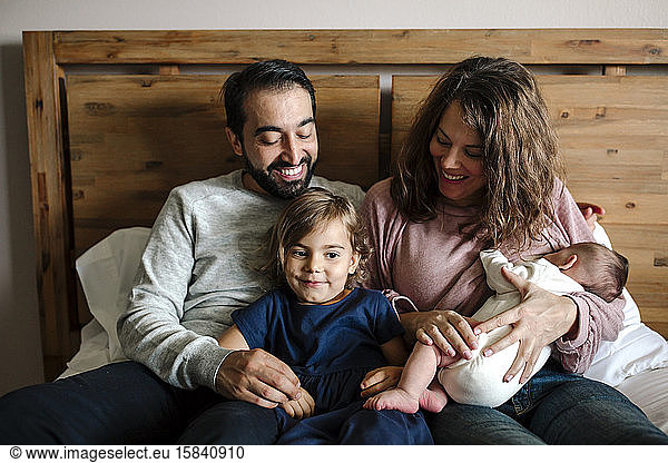 Smiling family snuggled together while mom breastfeeds newborn