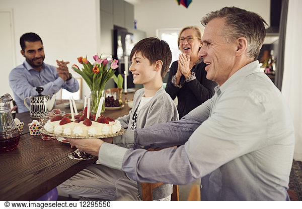 Smiling family with birthday cake enjoying at party