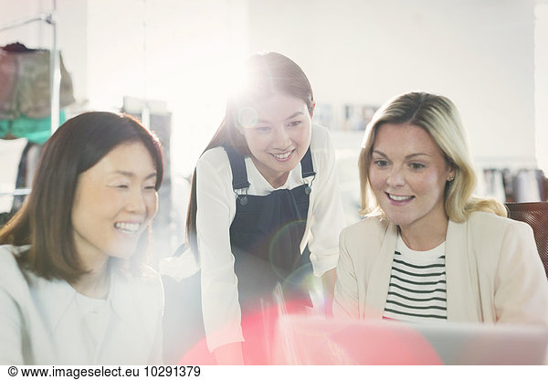 Smiling fashion designers working at laptop in office