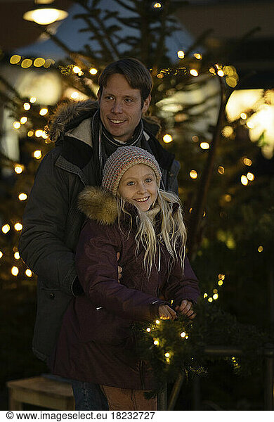 Smiling father and daughter at Christmas market at night