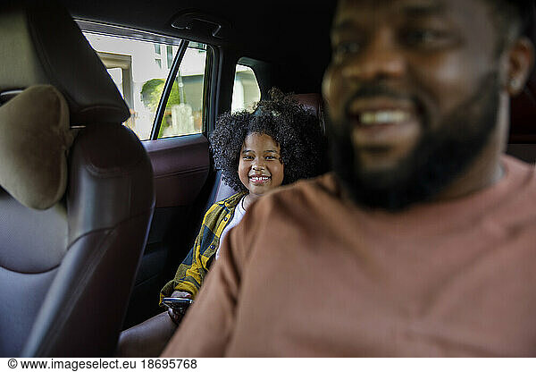 Smiling father and daughter sitting in car