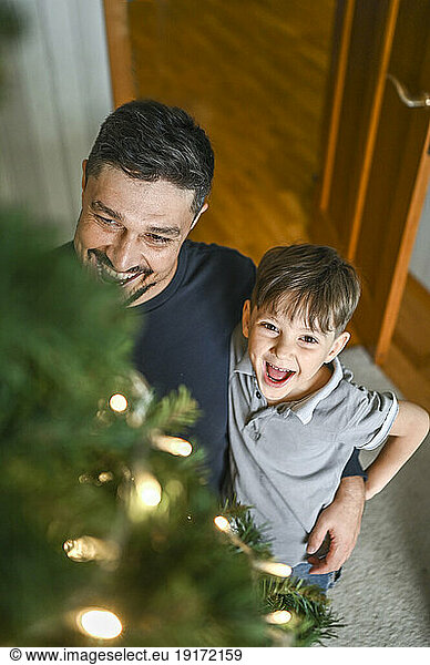 Smiling father and son looking at decorated r Christmas tree