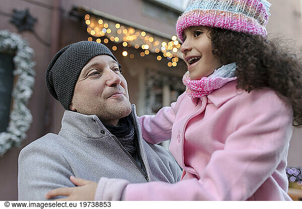 Smiling father carrying daughter at Christmas market